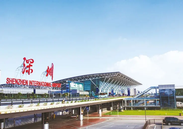 现代化开放式办公空间,大面积落地窗采光充足,员工在工位上专注工作,绿植点缀其间